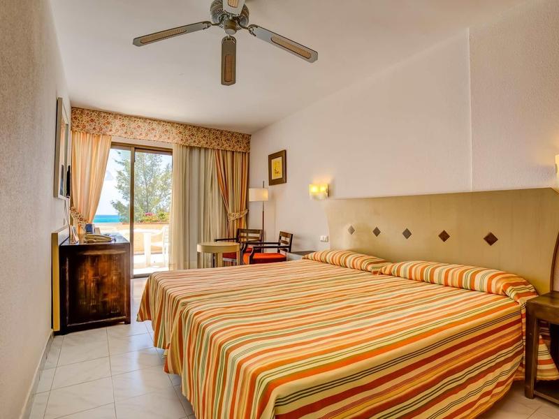 Camera d'hotel luminosa con due letti singoli e vista sul balcone.