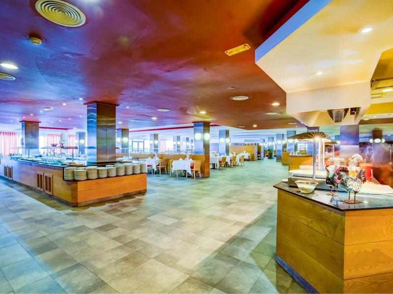 Ampia e luminosa sala da pranzo con molti tavoli e illuminazione moderna in un hotel.