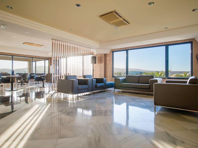 Ampia area lounge con divani moderni e grandi finestre con vista sulla natura.