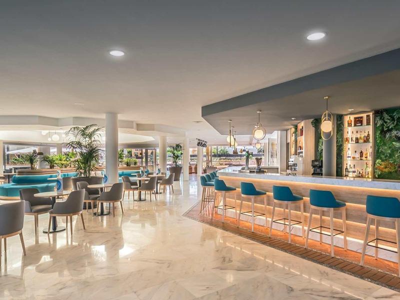 Spacious hotel lobby with bar area, modern seating, and polished marble floors under warm lighting.