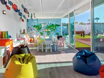 Bright hotel kids' playroom with colorful bean bags, small tables, chairs, and a world map mural.