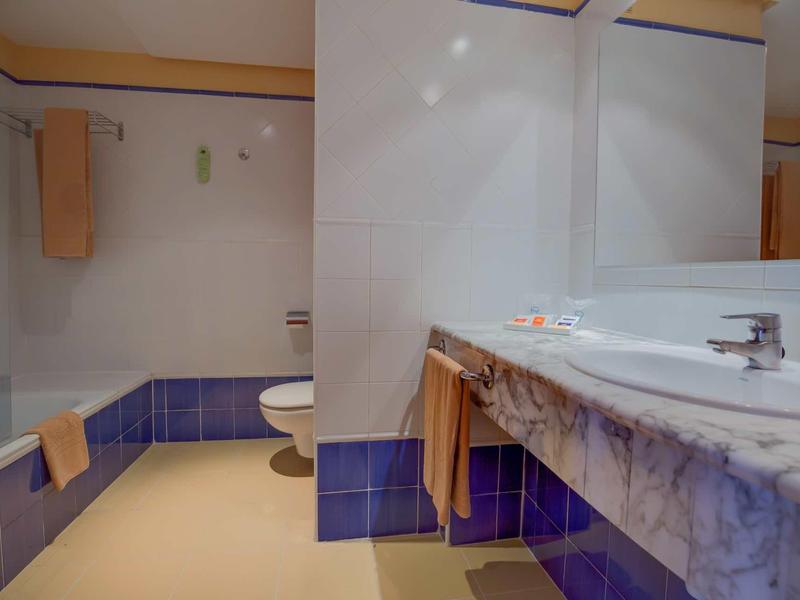 Bagno con lavabo, WC e vasca da bagno, piastrelle blu e bianche.