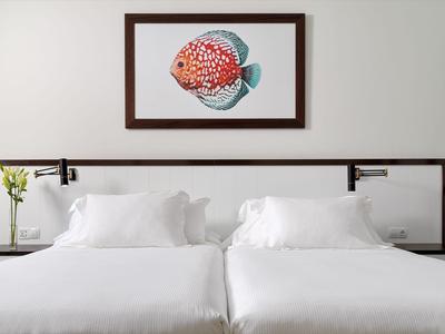 Modern hotel room with two white twin beds, night lamps, and a fish painting on the wall.