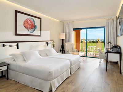 Camera d'hotel luminosa con due letti, pavimento in legno e balcone con vista panoramica