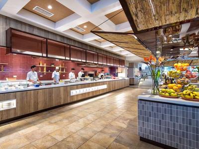 Großer Buffetbereich mit warmem Holz, heller Beleuchtung, Obstdekoration und mehreren Essensstationen.