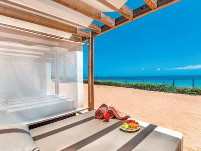 Offene Terrasse mit zwei Liegestühlen, Obstschale und Blick auf Strand und blaues Meer.