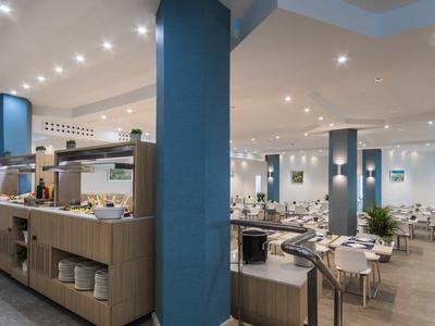 Salle à manger d'hôtel moderne avec plusieurs tables et coin buffet.