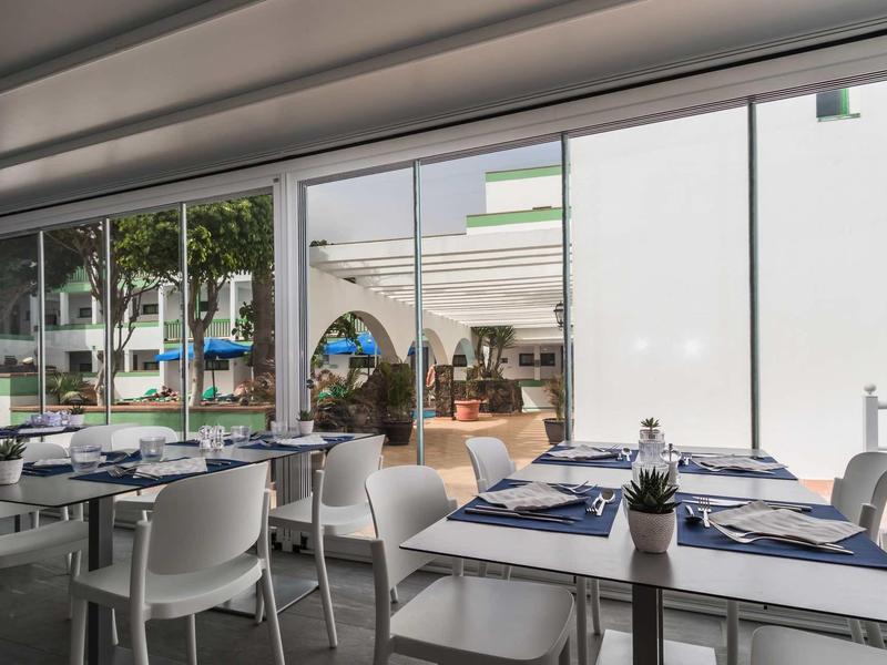 Restaurant moderne avec chaises blanches et tables dressées donnant sur l'extérieur.