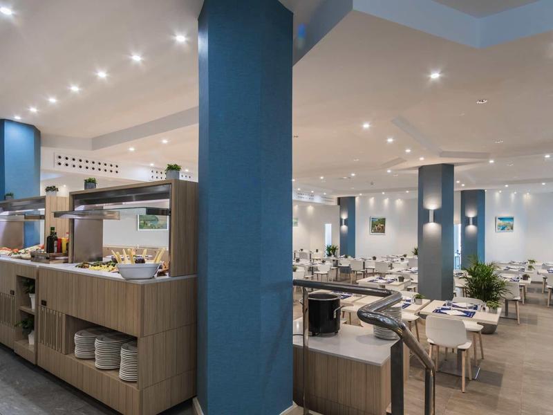 Salle à manger d'hôtel moderne avec plusieurs tables et coin buffet.