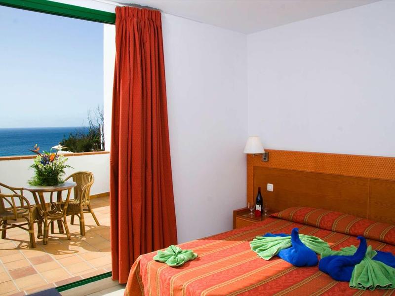 Chambre d'hôtel avec lit double et accès à une terrasse avec vue sur la mer.