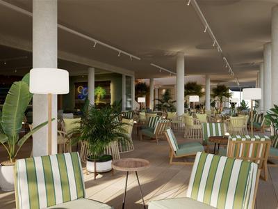 Spacious hotel lounge with striped chairs, round tables, and numerous green plants.