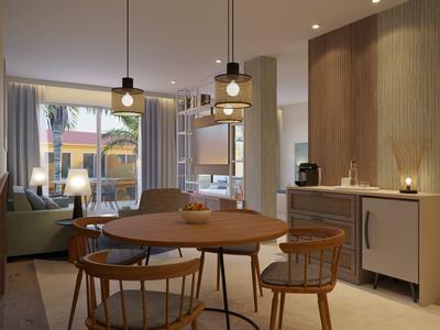 Modern hotel dining area with round table, wooden chairs, pendant lights, and outdoor view.