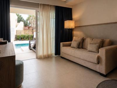 Gemütliches Hotellounge mit Sofa, Schreibtisch, Lampe und Blick auf den Pool im Freien.