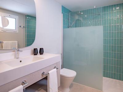 Modernes Badezimmer mit weißem Waschtisch, Toilette und grün gefliestem Duschbereich.