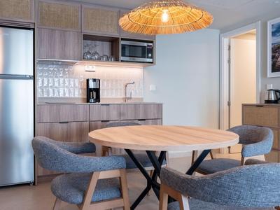 Moderne Küchenecke mit rundem Holztisch, grauen Stühlen und Edelstahlgeräten.