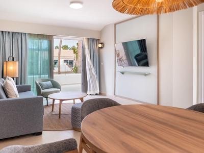 Modern eingerichtetes Wohnzimmer mit grauer Couch, TV und Blick auf Terrasse.
