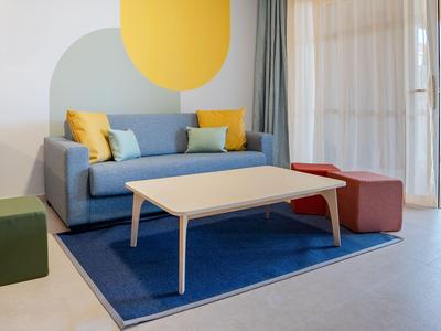 Moderne Hotellounge mit blauem Sofa, blauem Teppich und hellen Holzmöbeln.