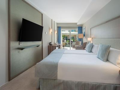 Moderner Hotelzimmer mit Doppelbett, Fernseher an der Wand und Balkon mit Blick ins Freie.