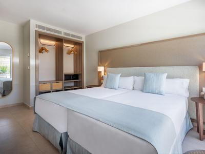 Modernes Hotelzimmer mit großem Bett, hellen Farben und offenem Kleiderschrank.