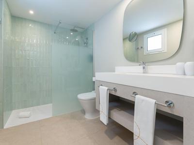 Modernes Hotelbad mit Glasdusche, großem Spiegel und weißen Handtüchern.