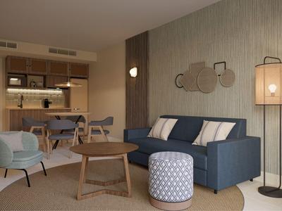 Cozy hotel lounge with blue sofa, round wooden tables, armchairs, and dining area in background.