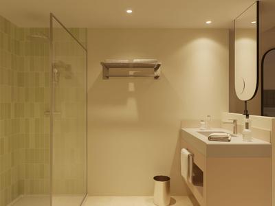 Modern bathroom with glass shower, beige walls, and double sink vanity under large mirror.