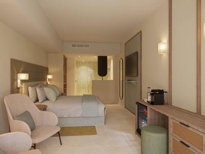Modern hotel room with double bed, armchair, wooden desk, and soft lighting.