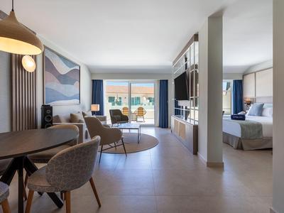 Chambre d'hôtel moderne avec coin salon, coin repas et chambre à coucher.