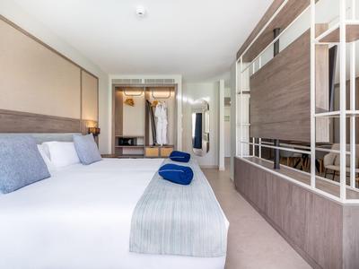 Chambre d'hôtel lumineuse avec grand lit, serviettes bleues et intérieur moderne.