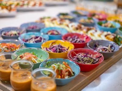 Saladiers colorés et sauces dans de petits bocaux sur un plateau pour un buffet d'hôtel.