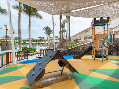 Aire de jeux moderne avec équipements d'escalade et sol coloré dans un hôtel tropical.