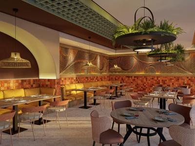 Cozy restaurant with warm lighting, upholstered seating, and green plants in circular ceiling fixtures.