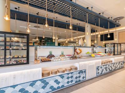 Moderne Buffetstation mit beleuchteten Regalen, verschiedenen Speisen und offener Küche im Hotel.