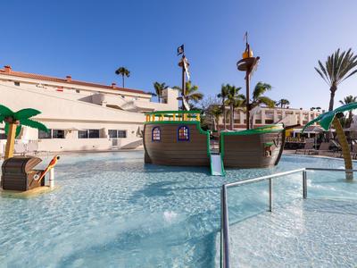 Aire de jeux aquatique pour enfants avec bateau pirate et piscine peu profonde dans un hôtel.