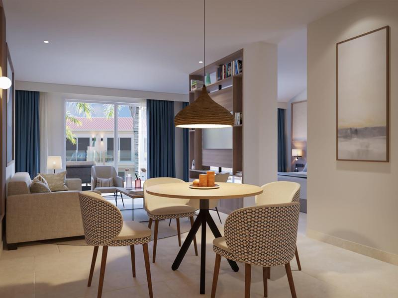 Modern hotel suite with dining area, cozy seating, large windows, and warm lighting.