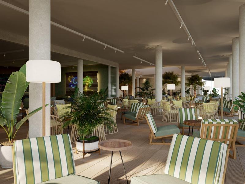 Spacious hotel lounge with striped chairs, round tables, and numerous green plants.