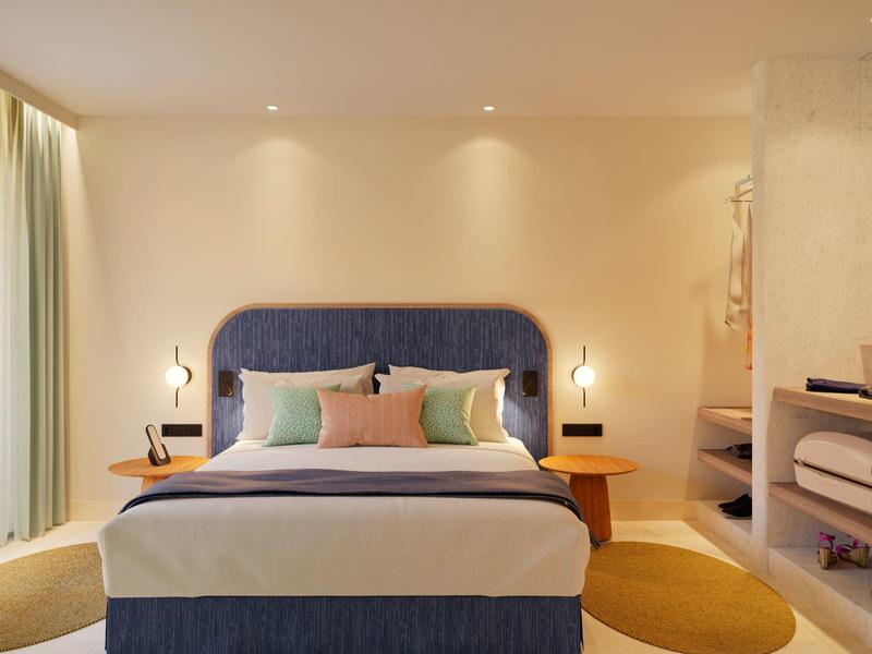 Cozy hotel room with a large bed, soft pillows, modern lamps, and warm lighting.