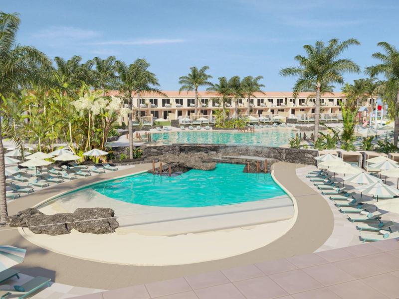 Resort pool area with palm trees, lounge chairs, umbrellas, and a hotel building in the background.