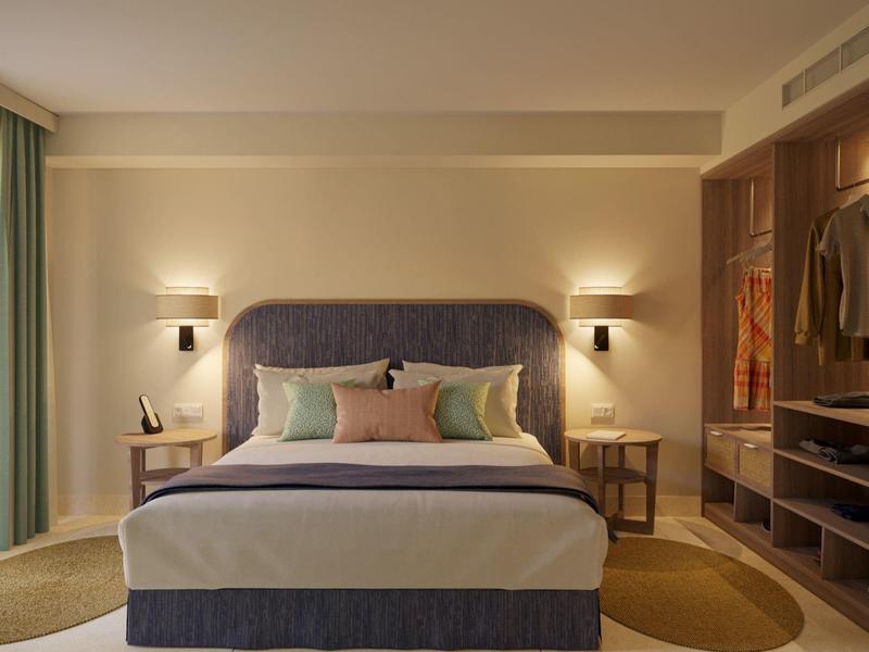 Modern hotel room with a large bed, bedside tables, soft lighting, and an open wardrobe.