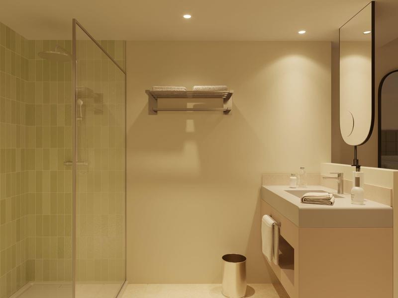 Modern bathroom with glass shower, beige walls, and double sink vanity under large mirror.