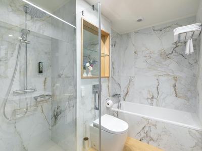 Salle de bain lumineuse avec baignoire, toilettes et douche à porte vitrée.