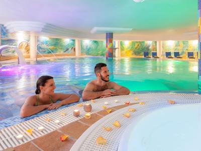 Un couple se détend dans un jacuzzi avec piscine intérieure colorée.