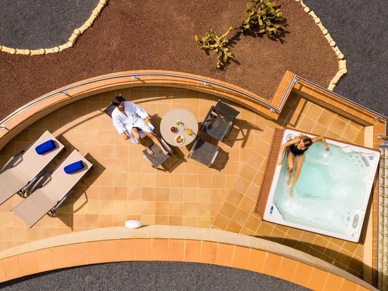 Vue aérienne d'une terrasse avec deux chaises longues, une table avec deux chaises et un jacuzzi.