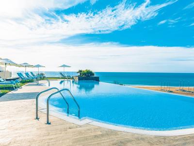 Piscina a sfioro con vista sul mare e lettini sotto ombrelloni.