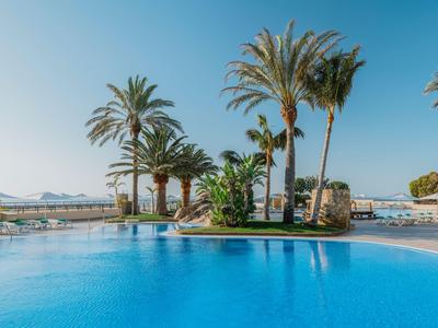 Piscina dell'hotel con palme sotto un cielo azzurro limpido e vista sulle montagne sullo sfondo