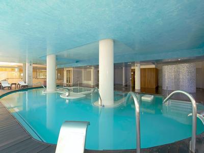 Innen-Pool mit blauer Decke, Säulen, Treppen und Holzfußboden, viel Tageslicht.