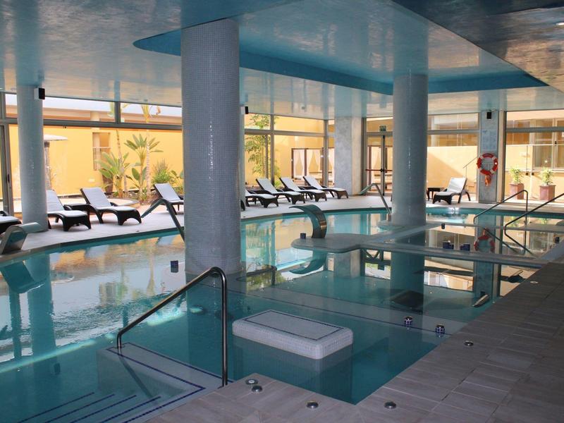 Wewnętrzny basen z leżakami ustawionymi przy dużych oknach i czystą wodą.