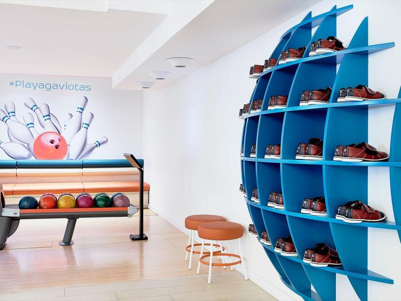 Nowoczesna kręgielnia z niebieskimi półkami na buty i kolorowymi kulami na eleganckiej podłodze.