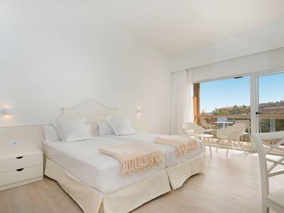 Hell eingerichtetes Schlafzimmer mit zwei Einzelbetten und großem Fenster zur Terrasse.