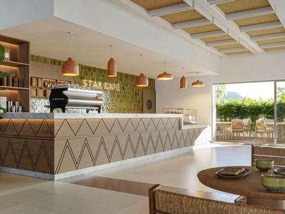 Bar dell'hotel moderna con bancone luminoso e posti a sedere, ricca di luce naturale.